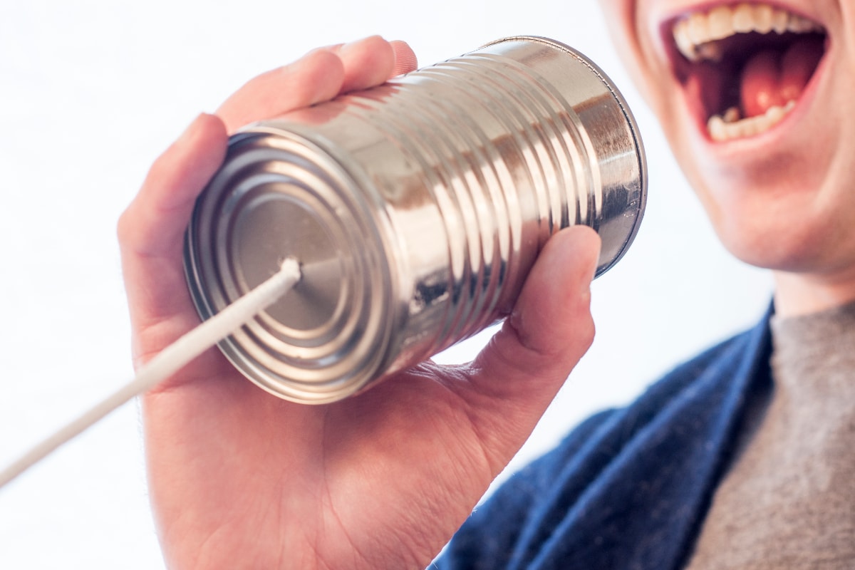 photograph picture of a man shoutig into a tin can telephone