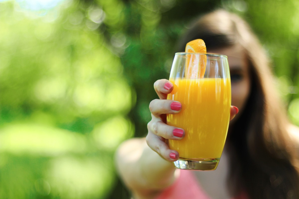 photograph picture of a woman offering a glass of orange juice