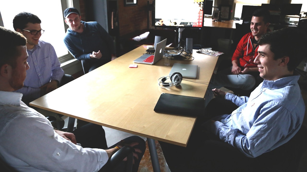photograph picture of five men in office sitting around a table for meeting