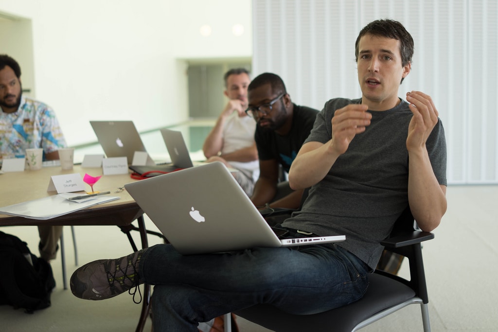 photograph picture of five men in office sitting around a table