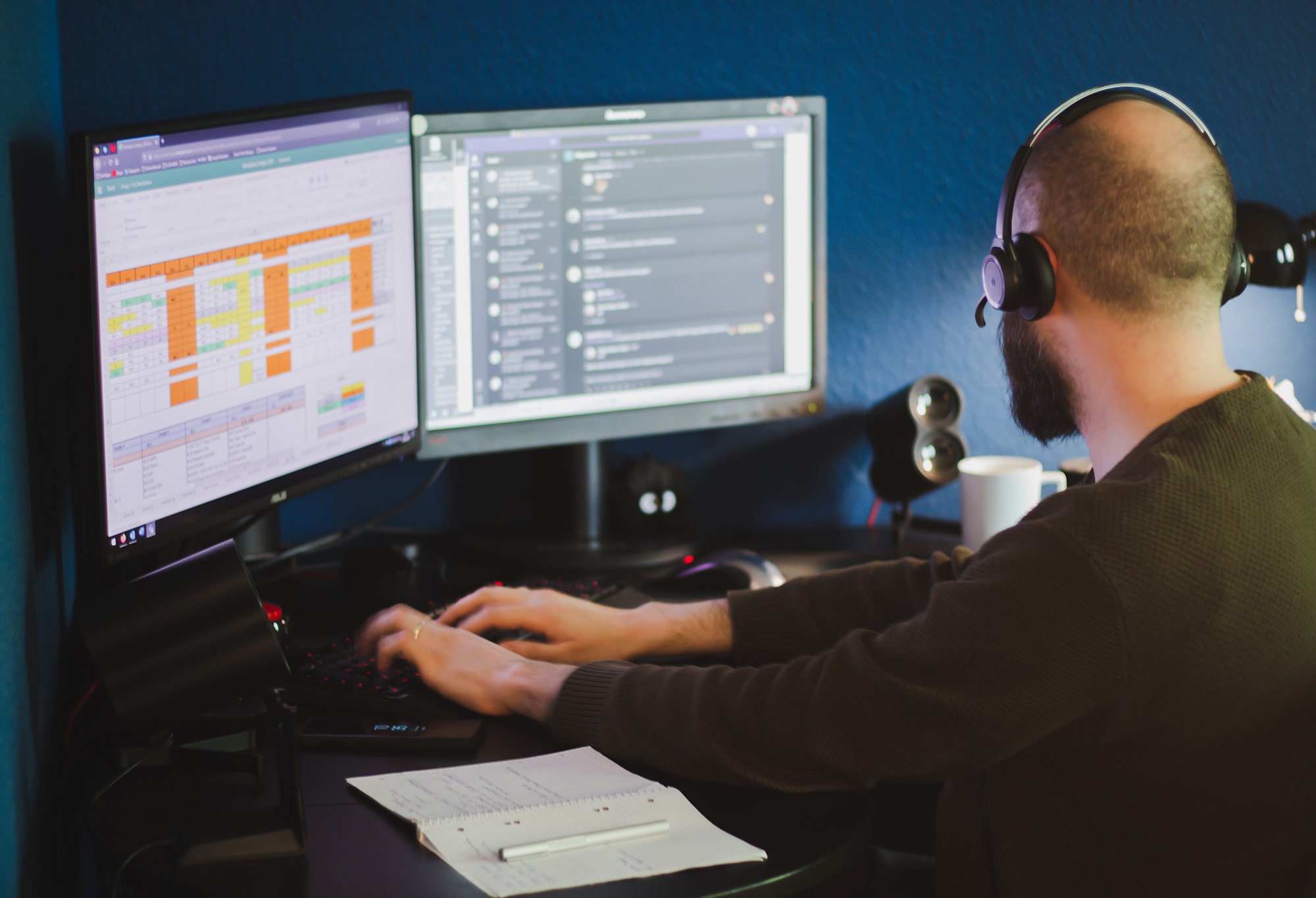 image of man wearing a headset while working on two monitors from home