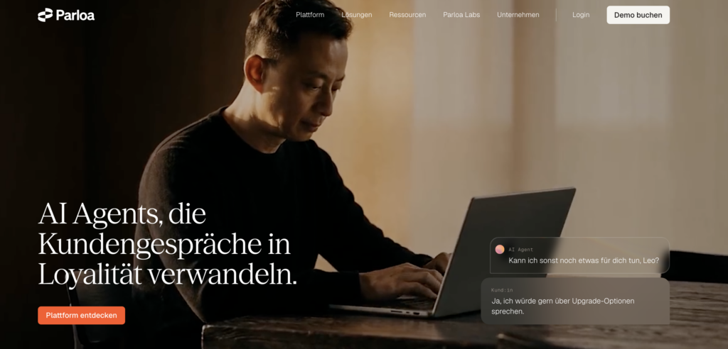 A man works on a laptop while a live chat interface demonstrates AI-driven customer interactions. Text on the screen states, 'AI Agents, die Kundensgespräche in Loyalität verwandeln'.