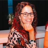 woman wearing glasses and a leopard print top smiling at the camera with her hand under her chin